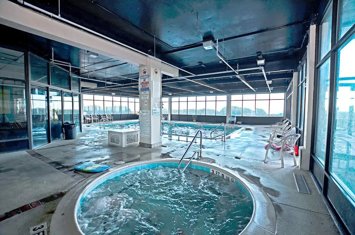 A bright indoor pool area with a hot tub, large windows, and plenty of space for families to relax and swim. The setting is cheerful and inviting, showing amenities available for refreshing breaks from the sun or rainy days.