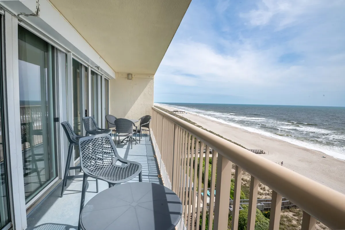 An inviting balcony scene with new wicker furnishings, a small table and chairs arranged for morning coffee or sunset toasts, and a sweeping ocean view. The tranquil setting highlights the private retreat atmosphere and directly references the balcony features discussed in the section.
